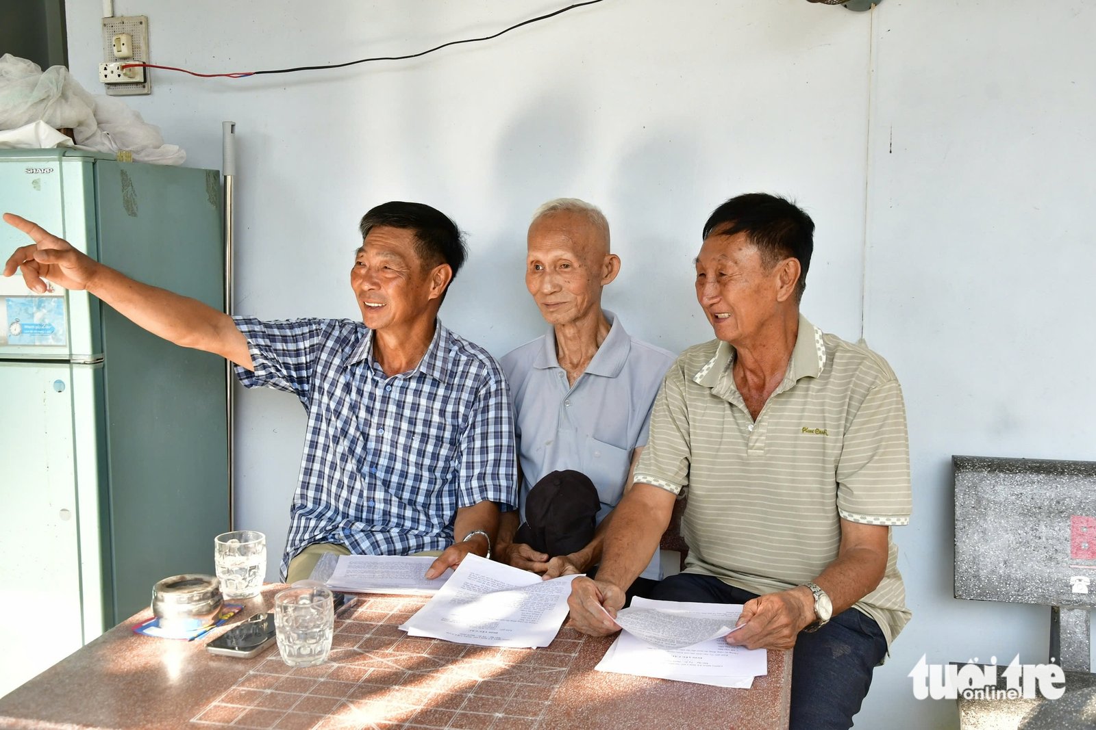 Ông Đỗ Văn Bảy (bìa trái) và người dân trong ấp xem lại những lá đơn yêu cầu, ki